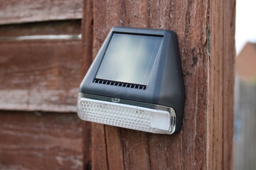 Solar powered outdoor LED light attached to a wooden fence post
