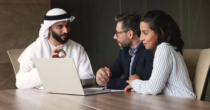 Real estate agent in traditional muslim robe showing presentation on laptop, make commercial offer to couple. Family and bank advisor talking during meeting, discuss deal, discuss buy company services