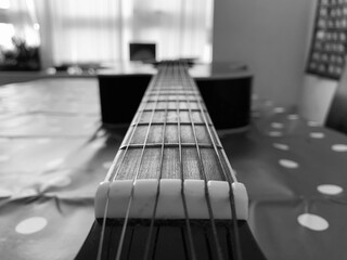 A 6 String acoustic guitar close up focus on top of fret board