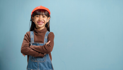 A little girl is wearing a engineer hat, is happy to learn.