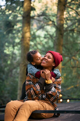 Loving black mother and daughter enjoy in camping trip in forest.