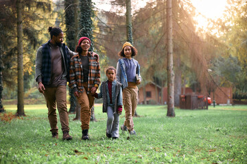 Black parents with kids enjoying in autumn walk in forest.