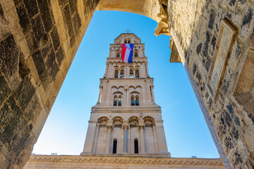 Cathedral of Saint Domnius' bell tower with Croatian flag waving in the wind in  Diocletian palace, Split, Croatia. Diocletian palace UNESCO world heritage site in Split, Croatia - obrazy, fototapety, plakaty