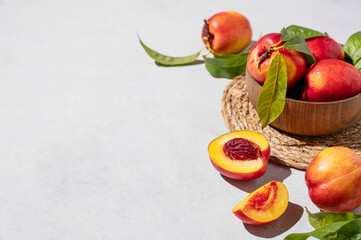 Juicy and sweet nectarines in a bowl on a light background with shadow. Healthy organic farm fruit concept.