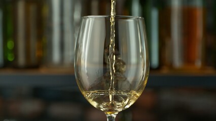 Pouring White Wine into Glass on Dark Background.