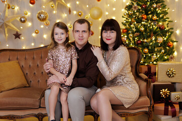 Happy family sitting in christmas decorated room in gold colours