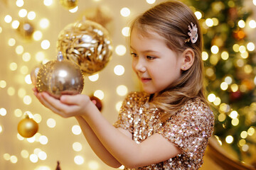Naklejka premium Cute little girl holding golden christmas ball