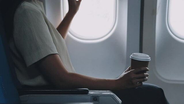 portrait of A successful asian business woman or female entrepreneur in formal suit in a plane sits in a business class seat and drink coffee during flight, relax concept