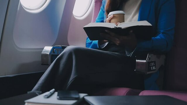 Successful female book editor reading literature during time in airplane before business meeting with writer, confident formally dressed woman enjoying international flight and leisure for novel