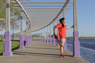 Latin girl stretching in the pergola of a public park.