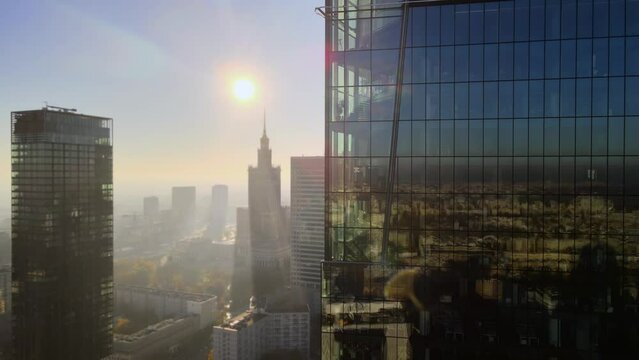 Modern business districtcity glass skyscrapers drone zoom in close to the buildings. Skyscraper in the big city top view during the sunrise when first sun rays are going through the glass windows.