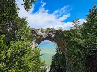 Arch Rock on Mackinac Island on Lake Huron shore in Michigan with summer sky and green trees