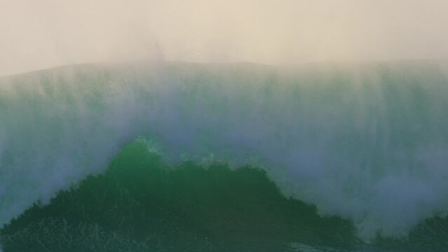 huge tsunami like wave crashing on a beach at sunset