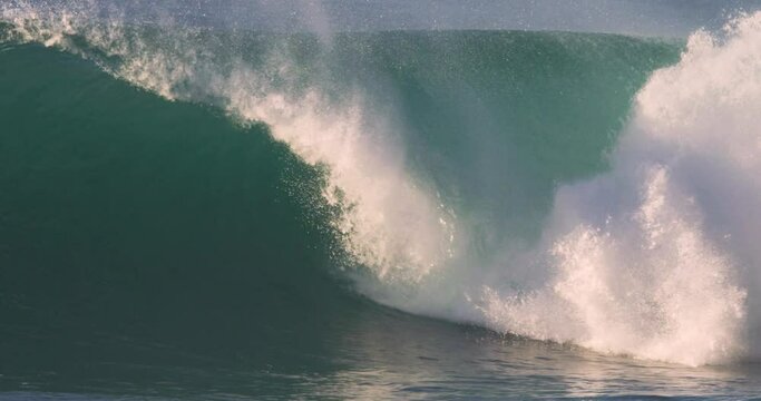 huge wave crashing in a wild ocean at sunset