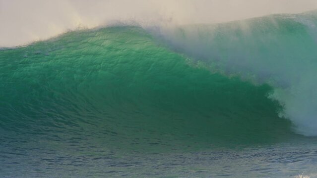 huge dangerous wave breaking in slow motion at sunset in the ocean