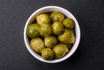 Delicious boiled Brussels sprouts on a ceramic plate on a dark concrete background