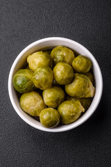 Delicious boiled Brussels sprouts on a ceramic plate on a dark concrete background