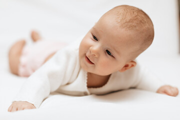 Funny infant girl in knitted clothes is lying on white background. Close up. Copy space. 