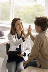 Vertical shot cheerful female pediatrician in uniform consult little boy patient at checkup meeting...