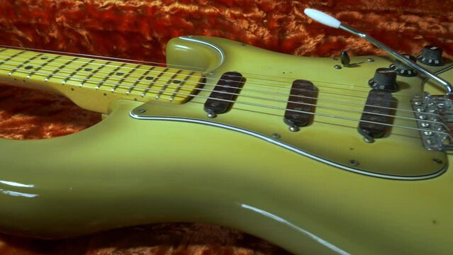 Closeup cinematic shot of a decades old, vintage electric guitar in its plush lined protective hard case.
