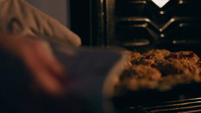Cookie. A middle-aged girl baked cookies on baking sheet at her workplace. Steady camera movement of diet-conscious girl taking out a baking sheet from a hot oven preparing breakfast, Thanksgiving Day