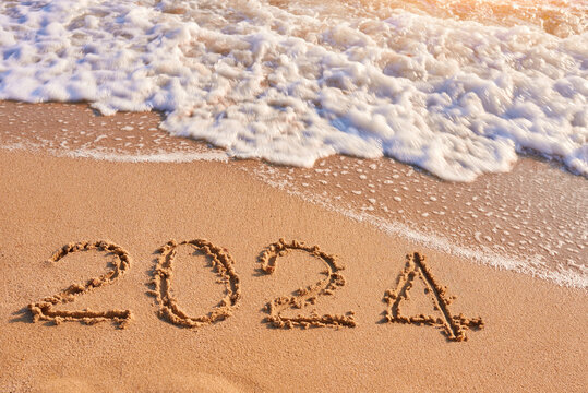 2024 year written on sandy beach sea at sunny day