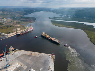 aerial view of a container ship is seen assisted by two tugboats as it departs the harbor