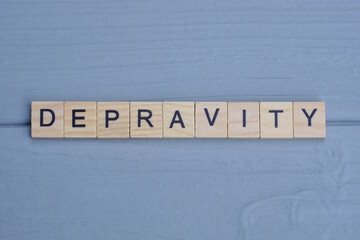 text the word depravity from brown wooden small letters with black font on an gray table