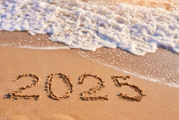 2025 year written on sandy beach sea at sunny day - obrazy, fototapety, plakaty