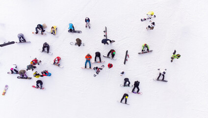 Aerial view of a crowd of snowboarders on a snowy slope, ready to start their descent.