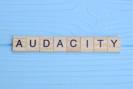 word audacity made from wooden gray letters lies on a blue background