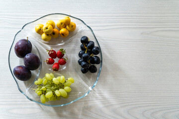 a plate of mixed fruits on the white table