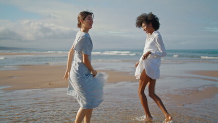 Happy girls dancing beach on summer weekend. Excited smiling lgbt couple enjoy