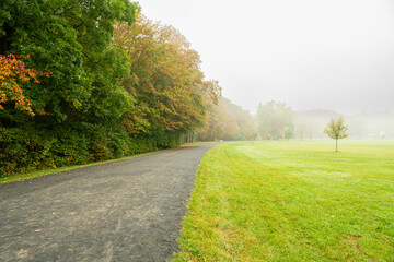 Fototapeta na wymiar Beautiful tranquil autumn scene in Gladstone Park, New Jersey featuring colorful fall foliage and fog on the background