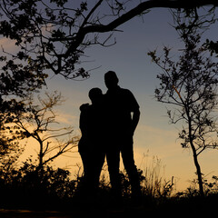 Umrisse eines nicht erkennbaren Paares vor stimmungsvollem Himmel nach Sonnenuntergang an der...