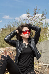 A photo of a girl in black clothes and red welding glasses on the counter area. People of the subculture. The other side of the city.