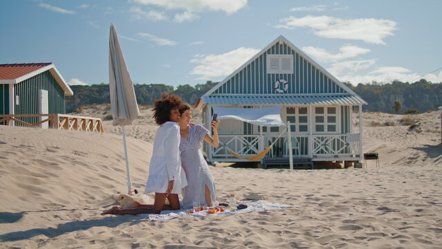 Relaxed girls taking selfie at ocean shore. Joyful lesbian couple resting beach