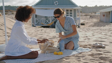 Homosexual women resting beach in summer morning. Two friends enjoying picnic