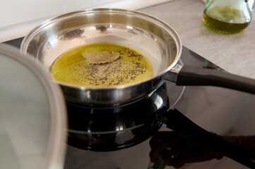 Still life with a frying pan with bay leaf, virgin olive oil and pepper on an electric stove