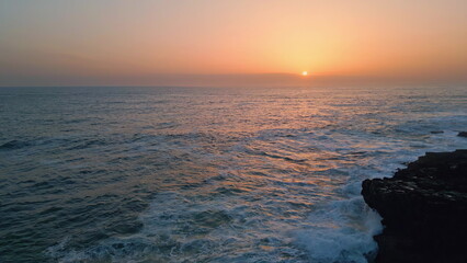 Stormy sea sunset horizon landscape slow motion. Foamy water crashing dark rocks