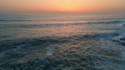 Morning marine surf splashing aerial view. Sunrise sea waves break on rock cliff