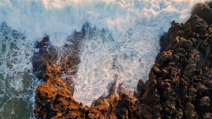 Aerial view stormy ocean waves breaking volcanic rocks. Water stream landscape