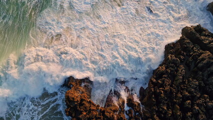 Stormy sea waves splashing seashore cliffs. Top aerial view ocean volcanic rocks