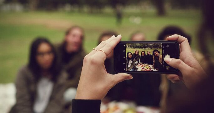 Hands, phone and photograph with friends in a park together for a reunion to capture a memory closeup. Technology, mobile screen and picture with a group of young people outdoor in a green garden