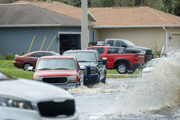 Hurricahe rainfall flooded Florida road with evacuating cars and surrounded with water houses in...