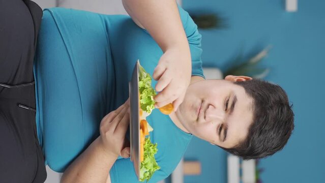 Vertical Video of Obesity boy thinks looking at unhealthy plate and can't decide.