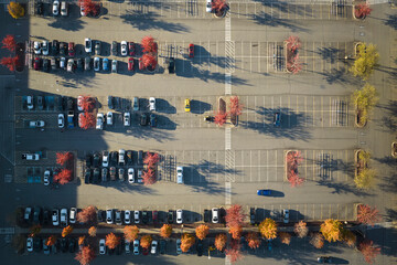 View from above of many parked cars on parking lot with lines and markings for parking places and...