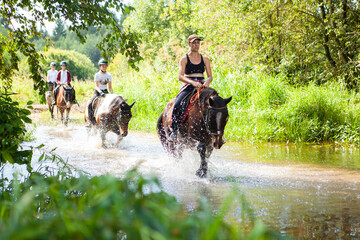 Horse ride, young girls riders, crossing a river on horseback.
