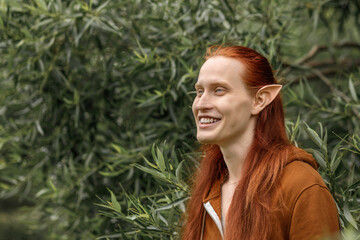 Artistic elf man with red hair and green eyes in the forest