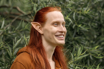 Artistic elf man with red hair and green eyes in the forest